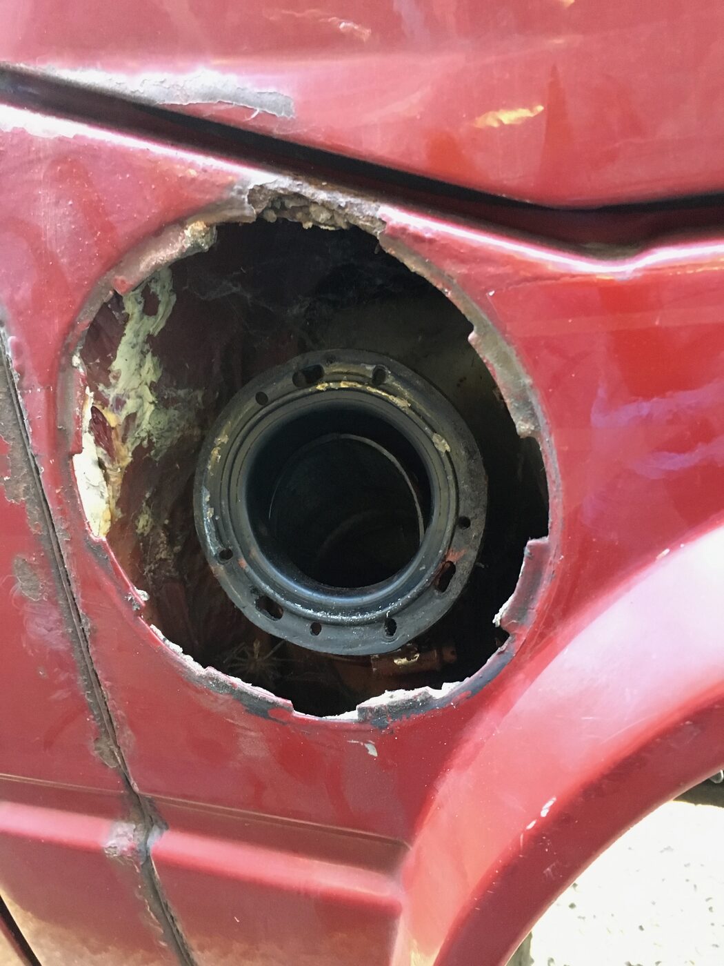 Stripped arch with rust around wheel-well opening — before any repair